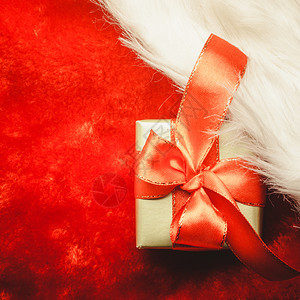 节日礼物圣诞节概念小金盒红背景上配有礼服的装饰弓图片