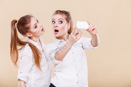 姐妹姊或最好的朋友两个学生金发女孩用智能手机相自拍照图片