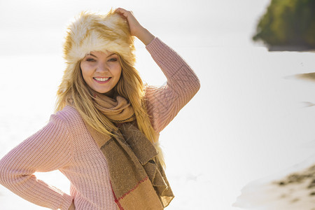 年轻女在秋天气期间海滩户外度过时间穿毛衣围巾和帽图片