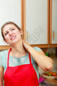 过度劳累的成年妇女因颈部疼痛而受苦在厨房到压力的成年妇女因颈部疼痛而受苦图片