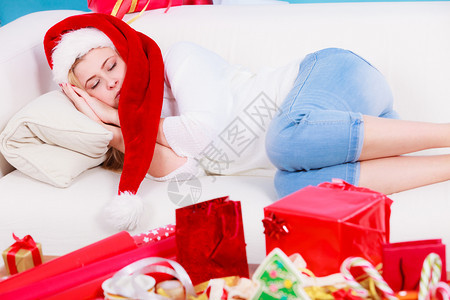 穿着圣诞礼帽的女孩在家睡沙发上等待礼物图片