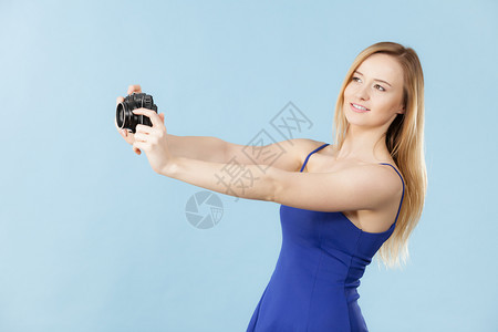 拍照片的女摄影记者拍照片的金发美女带着蓝背景相机的笑女金发美蓝背景相机的金发美女蓝色相机的金发美女图片