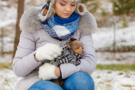 年轻悲伤的女子用温暖毛毯围巾裹住她最好的朋友小狗以在寒冷的冬天温暖他动物保护存收养概念悲伤的女孩在寒冷一天拥抱温暖她的狗图片