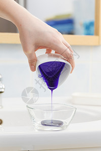 妇女将紫色头发染或洗水墨加到白碗中图片