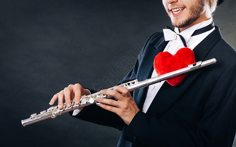 情人节爱旋律概念长笛音乐演奏男吹笛音乐演奏者年轻有乐器和红心的优雅时尚男子长笛和心的男子吹手爱情旋律图片