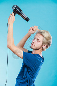 时尚和风格年轻时尚的男发型师理有变化外观的新念金发男子手持吹机和梳子在蓝色上制造新的发型戴吹机的特伦迪男子图片