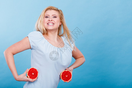 女微笑的孩将两半红葡萄果柑橘握在手中蓝色上健康饮食品暑假的乐趣概念女将葡萄果握在手中图片