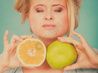 拿着春联拍照健康饮食新鲜物充满维他命闭着眼睛的妇女拿甜的柑橘水果