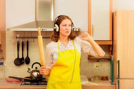 在家厨房做饭和穿着用滚动针跳舞的耳机可爱家庭主妇在厨房跳舞的家庭主妇图片