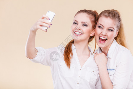 姐妹姊或最好的朋友两个学生金发女孩用智能手机相自拍照图片