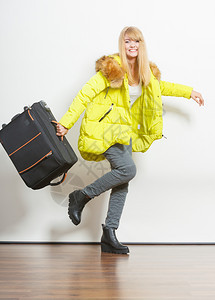 穿着温暖夹克的年轻快乐女人带着行李箱跑得很晚美丽的金发女游客旅行郎游图片