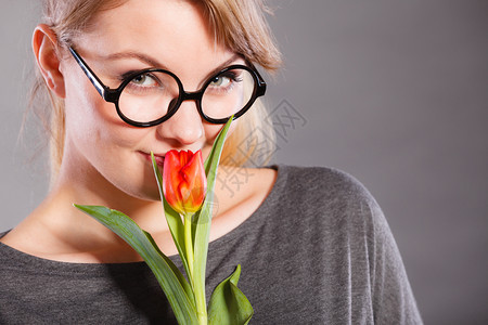 美丽情感自然的激眼镜概念纳迪女孩吸着花朵年轻的金发女随身士穿着红色郁金香的味纳迪女孩闻着花朵图片