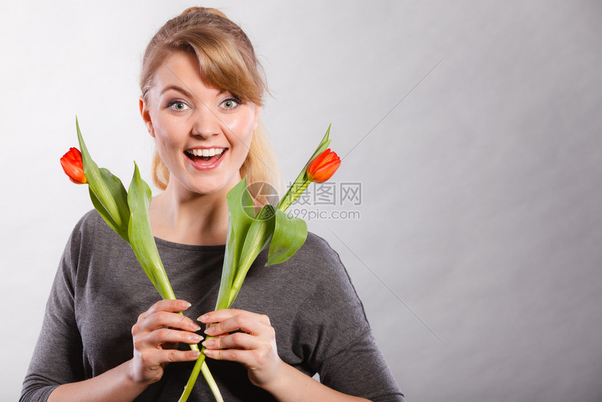 美貌植物时装青年放松概念美貌女孩拿着鲜花年轻女士拿着两张红郁金香图片