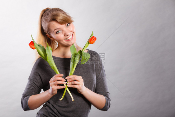 美貌植物时装青年放松概念美貌女孩拿着鲜花年轻女士拿着两张红郁金香图片