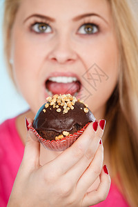 女人拿着美味巧克力蛋糕花生糖霜张开大嘴要咬了图片