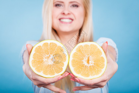 女微笑的孩将两半黄葡萄果柑橘握在手中蓝色上健康的食物饮概念女将葡萄果握在手中图片