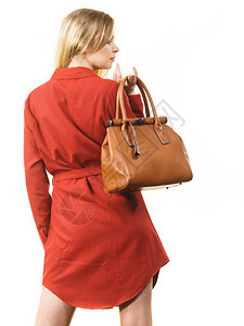 时尚的漂亮年轻女子穿着优雅的红色短裙并拿着皮包穿时髦的服装图片
