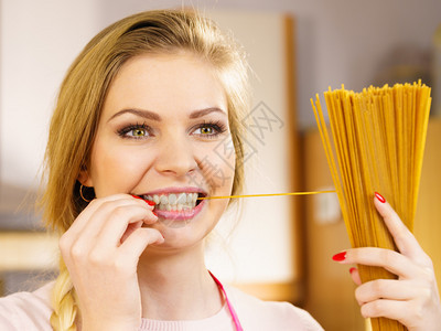 快乐的女士拿着长意大利面糊准备做饭健康的食物概念长的意大利面图片