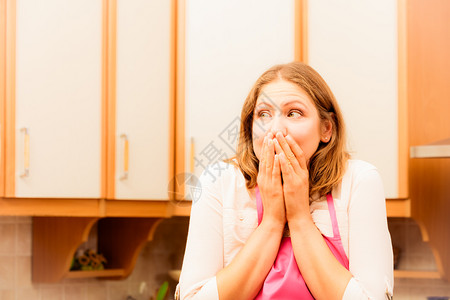 穿着粉色围裙的惊慌和担心女人厨房焦躁不安和紧张的家庭主妇消极的面部情绪过滤厨房的不幸家庭主妇背景图片