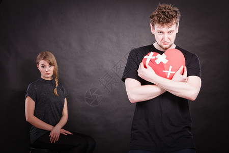 海边 夫妻心碎难恋的概念伤心不幸福的夫妻男女手拿纸红心用石膏绷带