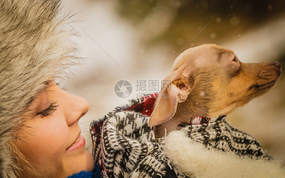 年轻女用毛毯围巾裹住她最好的朋友小狗在寒冷的冬季天温暖他动物保护存收养概念冬天女拥抱温暖她的小狗图片