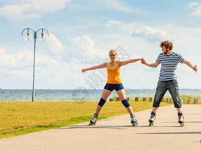 度假活跃的人和友谊概念穿滑溜冰雪的年轻情侣在海边户外玩滑雪冰男女在赛道上一起滚车图片