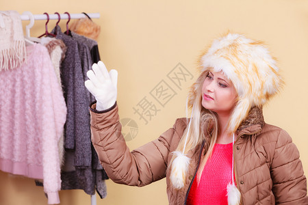 穿着寒冷的衣物和服装时概念穿着冬衣的金发女人穿着温暖的毛衣和外套站在柜里想着穿什么图片