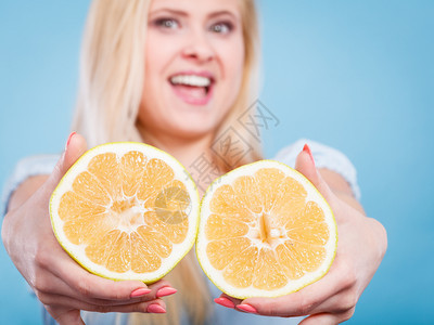 女微笑的孩将两半黄葡萄果柑橘握在手中蓝色上健康的食物饮概念女将葡萄果握在手中图片