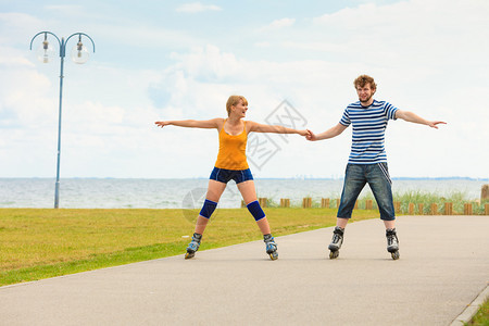 积极的生活方式和自由的理念一对穿着溜冰鞋的年轻情侣在海边户外溜冰女人和男人在一起享受时光图片