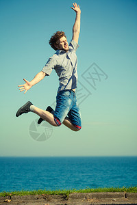 无忧虑的年轻人跳过海水快乐的男孩夏天幸福和自由图片