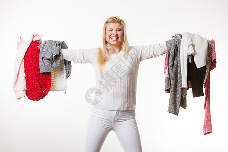 时装服两难概念妇女拿着一大堆温暖的冬衣不能决定穿什么白灰色图片