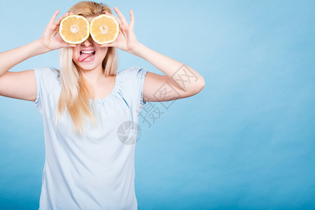 金发女少将两半黄葡萄果柑橘水握在手上蒙眼睛的蓝色健康饮食营养幸福的乐趣概念女孩用葡萄汁蒙在眼睛上图片