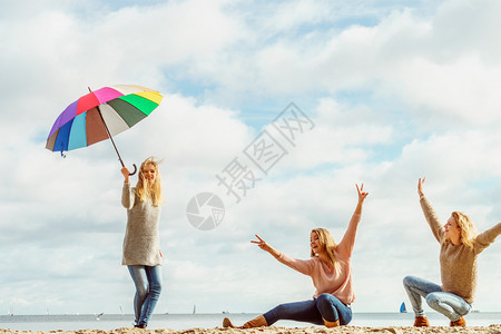 三个充满欢乐的女子在一起玩得很开心一个女人拿着多彩的雨伞女人拿着和朋友玩得开心图片