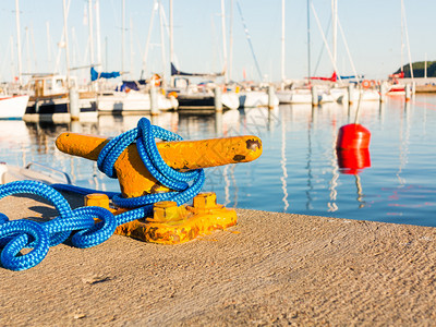 黄色系泊在船坞游艇上带蓝色绳子的黄系泊柱在背景中图片