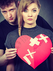 心碎难恋的概念伤心不幸福的夫妻男女手拿纸红心用石膏绷带固定关系裂痕伤心的夫妻抱着破碎的心图片