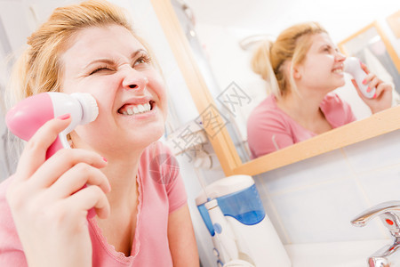 使用面部清洗刷机的惊吓尖叫妇女使用面部清洗刷子的惊吓妇女图片