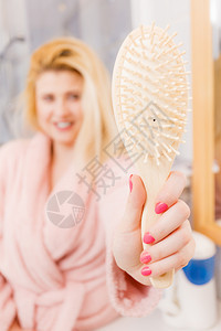 快乐的金发女郎拿着并展示她的梳子头发理和型概念快乐的女郎拿着她梳子图片