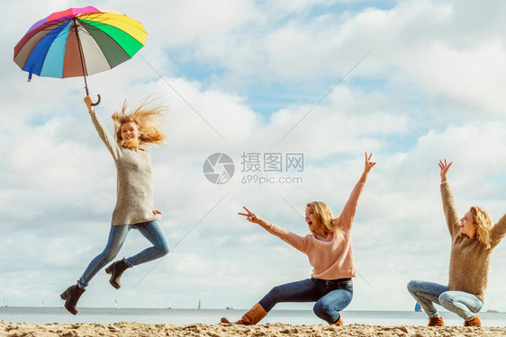 三个充满欢乐的女人带着多姿彩的雨伞到处跳女朋友在户外玩得开心图片