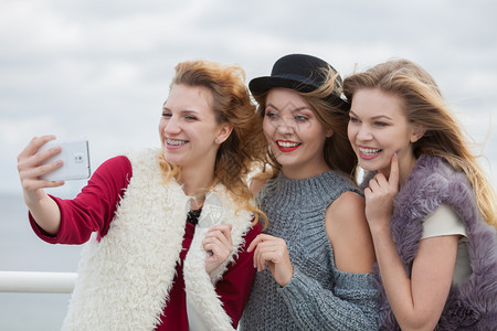 三位女自拍在户外用智能手机拍照三个女人在户外自拍图片素材
