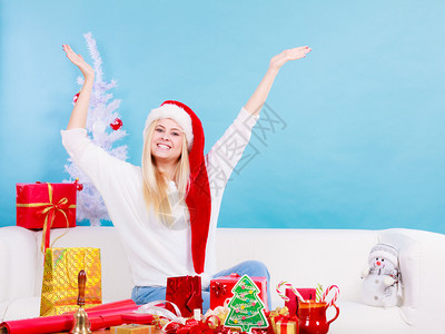 节日礼物季节概念戴圣诞帽的女人坐在沙发上准备圣诞礼物戴圣诞帽准备圣诞礼物的女人图片