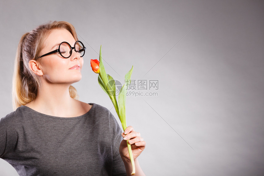 美丽的可爱女孩闻着美丽的春花可爱女孩的甜女人红色的绿郁金香女士闻到大自然的味道迷人鲜花闻到平静图片