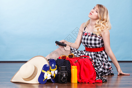 女人拿着望远镜坐在地板上拿着手提箱装满东西准备在暑假吃图片