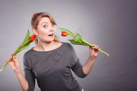 迷人的女士与花一起跳舞年轻的女士在周围挥舞着两个红色的郁金香图片