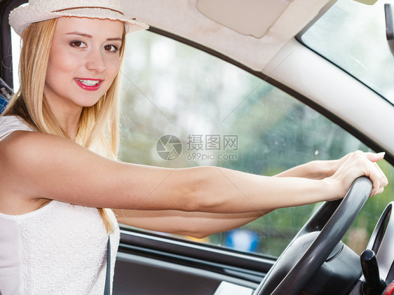 漂亮的女人坐在车里室内的车轮上笑着漂亮的金发女郎准备在假期旅行图片