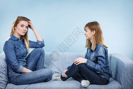 友谊人际关系概念两个穿着牛仔裤衬衫的严肃女朋友或姐妹在交谈论解决问题两个严肃的女朋友在沙发上交谈图片