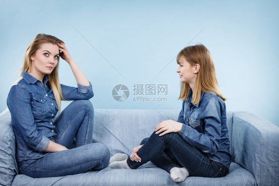 友谊人际关系概念两个穿着牛仔裤衬衫的严肃女朋友或姐妹在交谈论解决问题两个严肃的女朋友在沙发上交谈图片