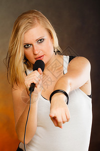 卡拉OK音乐歌手概念金发女人的肖像唱给麦克风年轻明星表演玩得开心摄影棚拍金发女人唱给麦克风图片