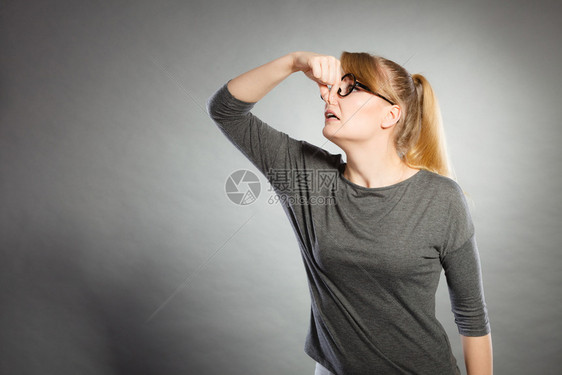 脏兮的卫生垃圾概念神经质女孩拿着鼻子戴眼镜的金发女孩拿着眼镜抓气味恶心的图片