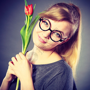 美丽情感自然的激眼镜概念纳迪女孩吸着花朵年轻的金发女随身士穿着红色郁金香的味纳迪女孩闻着花朵图片