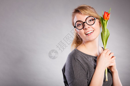 美丽情感自然的激眼镜概念纳迪女孩吸着花朵年轻的金发女随身士穿着红色郁金香的味纳迪女孩闻着花朵图片